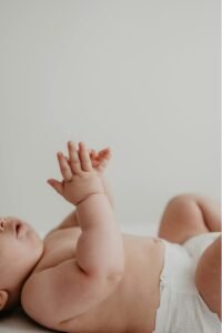 baby die op de rug ligt en in de handen klapt