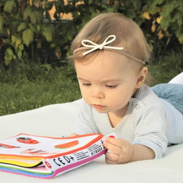 baby die op de buik ligt te spelen met een knisperboekje als activiteit